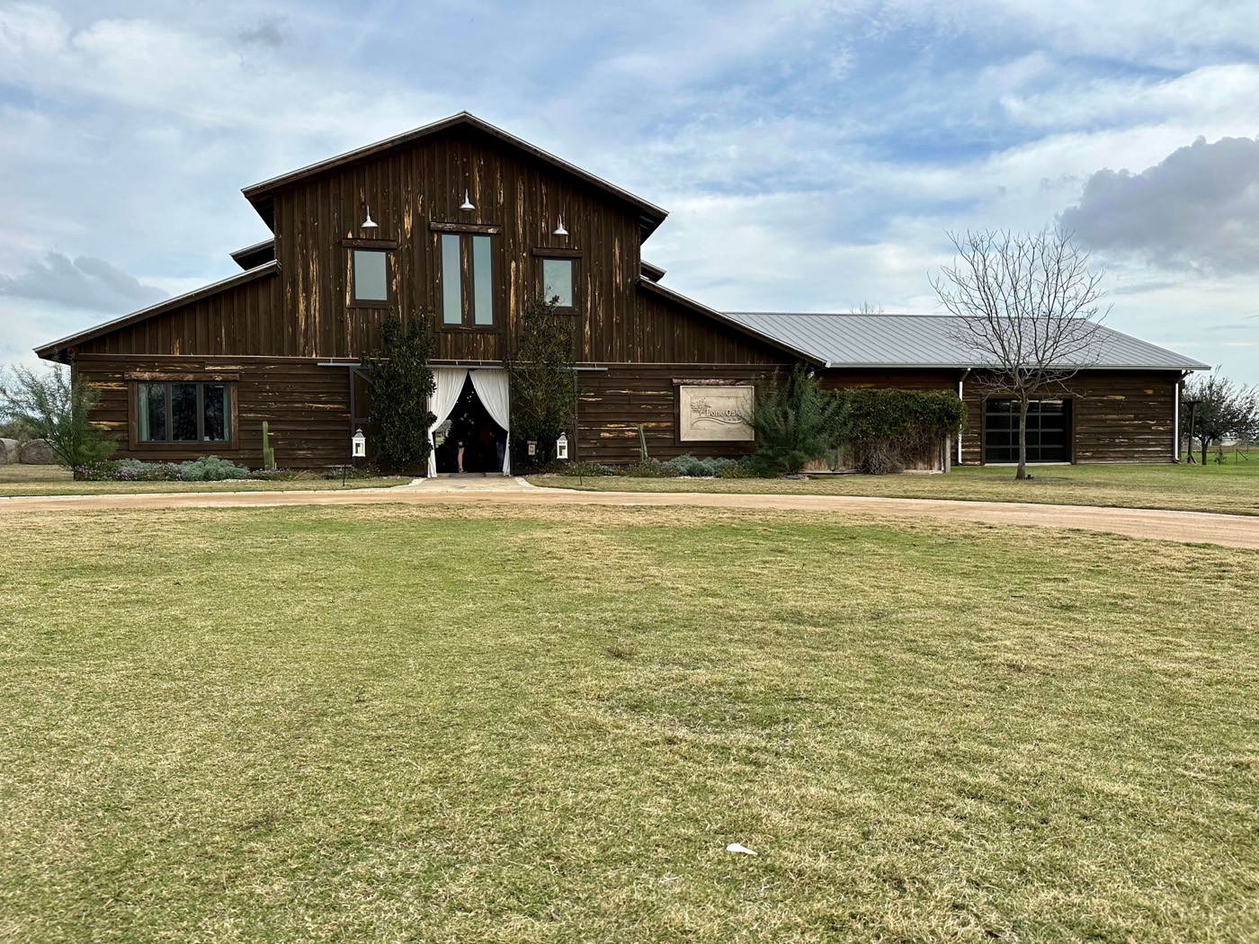 Rustic barn venue with a curtained entrance on open grounds