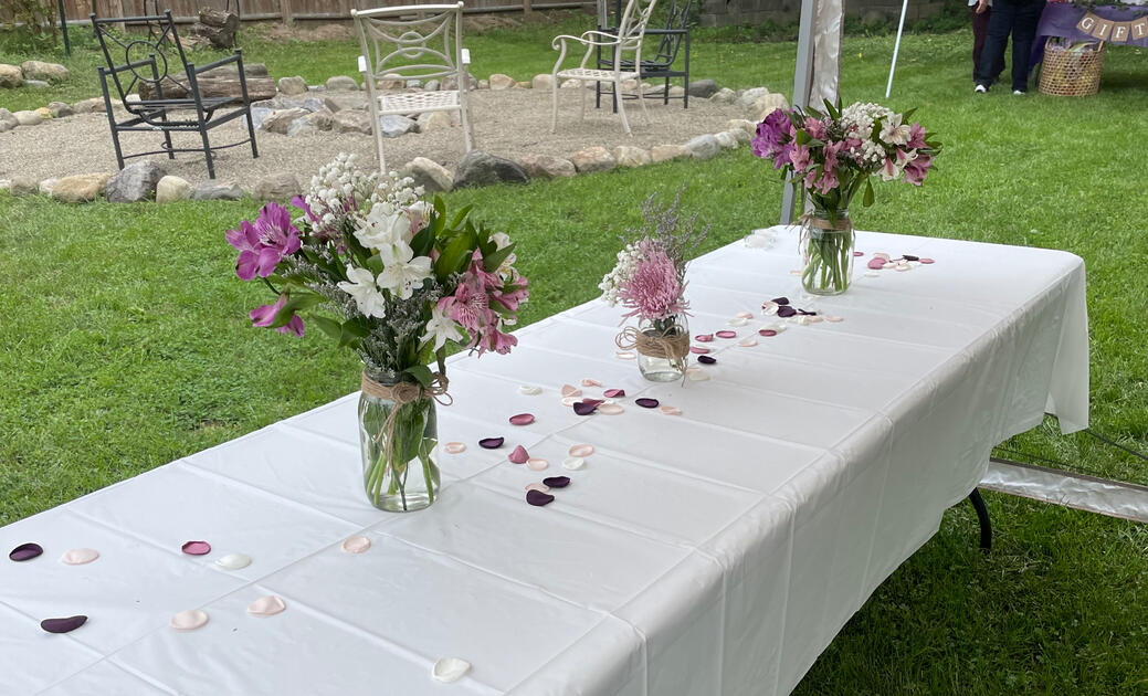 Outdoor table dressed with wildflower jars and scattered petals