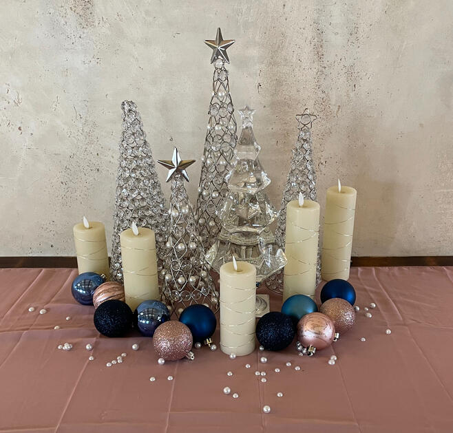 Winter tablescape of crystal trees, candles, and ornaments on dusty rose linen